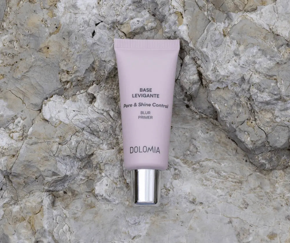 Dolomia Base Levigante Pore & Shine Control Blur Primer in fliederfarbener Tube mit silbernem Verschluss auf hellem Steinhintergrund.