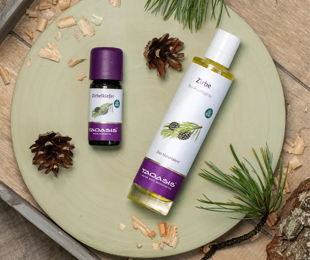 Taoasis Zirbe Bio Raumspray in weißer Flasche mit Pumpzerstäuber und Zirbenzapfen-Etikett, daneben Zirbelkiefer Öl auf Holzschale, Zaversky Stadtapotheke Knittelfeld