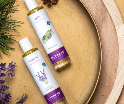 Taoasis Zirbe Bio Raumspray in weißer Sprühflasche neben Lavendel Raumspray auf Holztablett mit Zirbenzweigen und Lavendelblüten